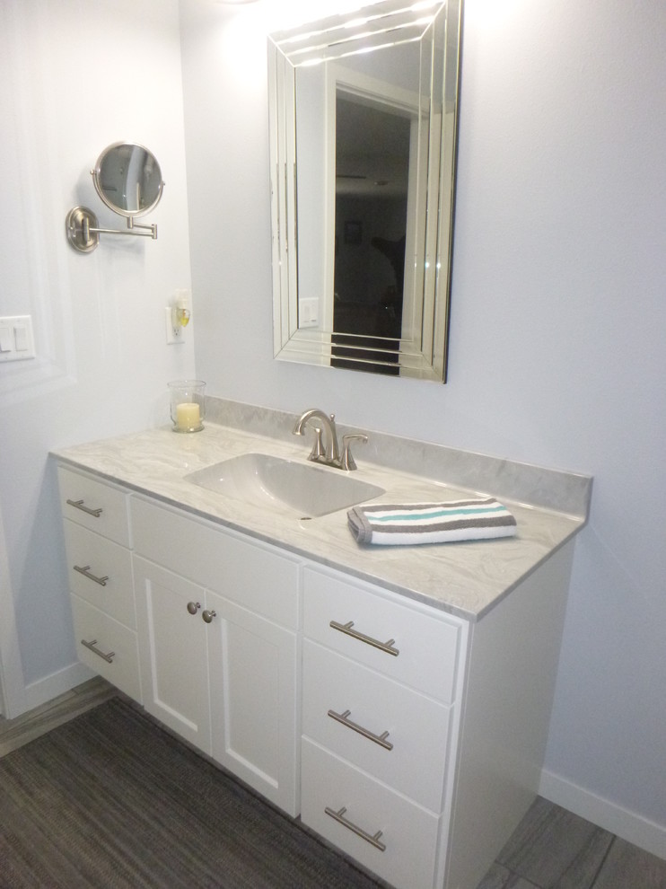 Photo of a mid-sized transitional kids bathroom in Minneapolis with shaker cabinets, white cabinets, blue walls, porcelain floors, an integrated sink, marble benchtops and grey floor.