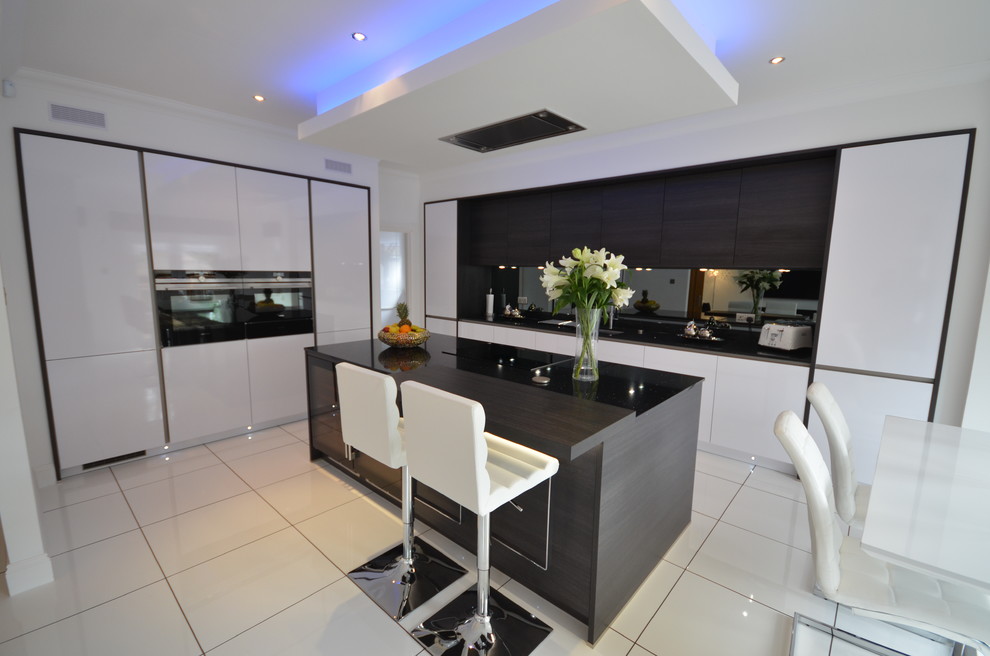 Mid-sized contemporary galley open plan kitchen in Other with a double-bowl sink, flat-panel cabinets, dark wood cabinets, wood benchtops, white splashback, porcelain splashback, white appliances, ceramic floors, with island and white floor.