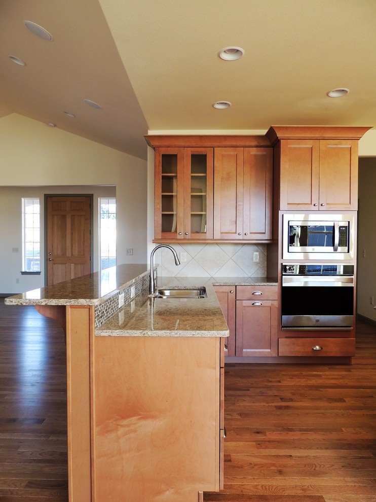 Large transitional u-shaped light wood floor eat-in kitchen photo in Seattle with recessed-panel cabinets, medium tone wood cabinets, multicolored backsplash, mosaic tile backsplash, stainless steel appliances, an island and quartz countertops