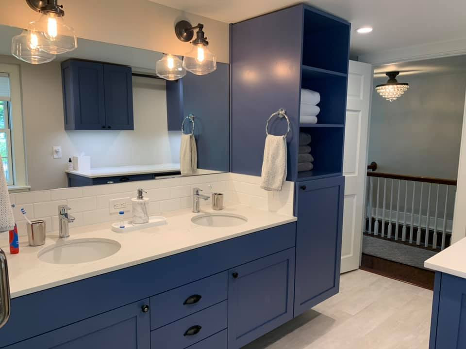 Inspiration for a mid-sized traditional kids bathroom in New York with beaded inset cabinets, blue cabinets, a corner shower, a one-piece toilet, blue tile, ceramic tile, grey walls, laminate floors, an undermount sink, grey floor, a hinged shower door, a laundry, a double vanity and a built-in vanity.