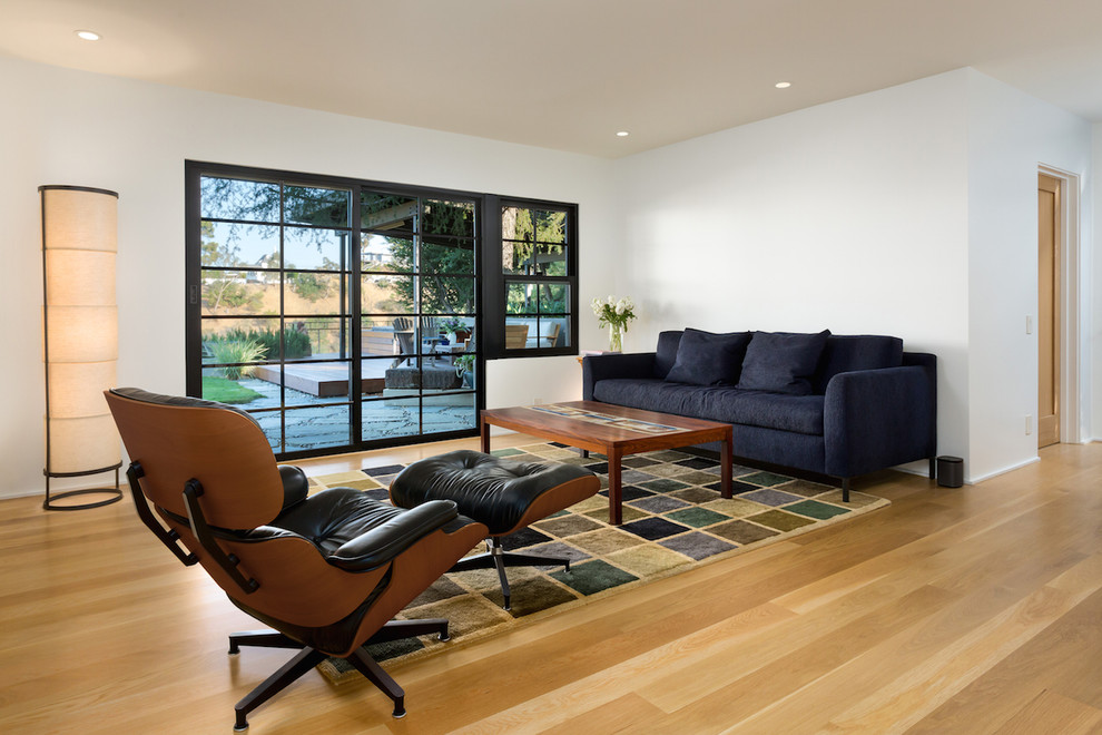 This is an example of a mid-sized midcentury enclosed family room in Los Angeles with white walls, light hardwood floors, no fireplace and yellow floor.