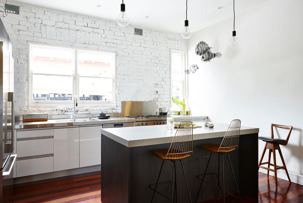 Photo of an industrial kitchen in Sydney with an integrated sink, flat-panel cabinets, white cabinets, stainless steel appliances, dark hardwood floors and with island.