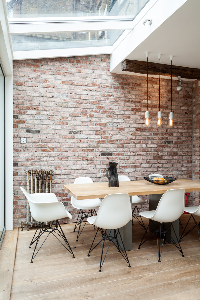 Design ideas for a mid-sized industrial dining room in London with light hardwood floors.