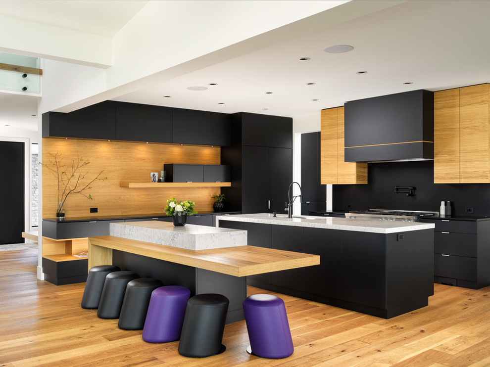 Inspiration for a mid-sized modern l-shaped kitchen pantry in Other with a drop-in sink, flat-panel cabinets, black cabinets, solid surface benchtops, black splashback, timber splashback, stainless steel appliances, light hardwood floors, multiple islands, beige floor and white benchtop.