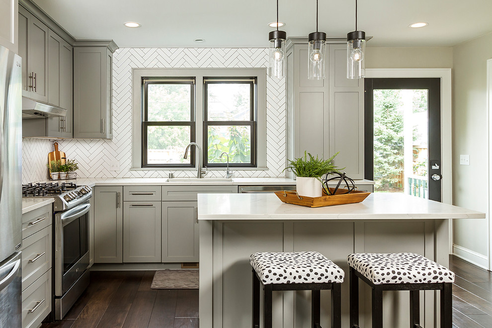 Mid-sized transitional l-shaped dark wood floor and brown floor kitchen photo in Minneapolis with an undermount sink, shaker cabinets, gray cabinets, quartzite countertops, white backsplash, stainless steel appliances, an island, white countertops and ceramic backsplash