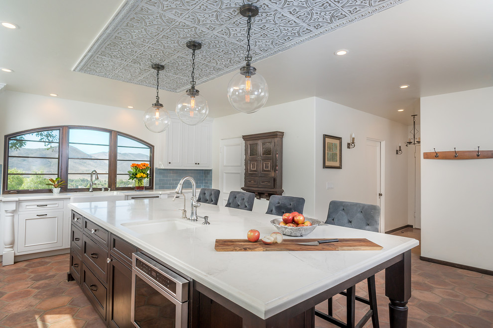 Expansive mediterranean separate kitchen in Los Angeles with a farmhouse sink, beaded inset cabinets, white cabinets, quartzite benchtops, blue splashback, cement tile splashback, stainless steel appliances, ceramic floors and with island.