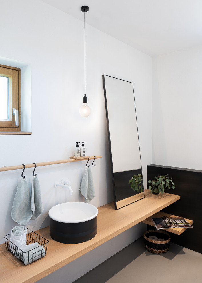 Inspiration for a scandinavian powder room in Munich with white walls, concrete floors, a vessel sink, wood benchtops, beige benchtops and grey floor.