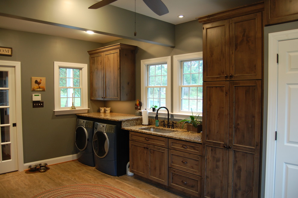 This is an example of a large traditional galley utility room in DC Metro with an undermount sink, granite benchtops, grey walls, a side-by-side washer and dryer, recessed-panel cabinets and dark wood cabinets.