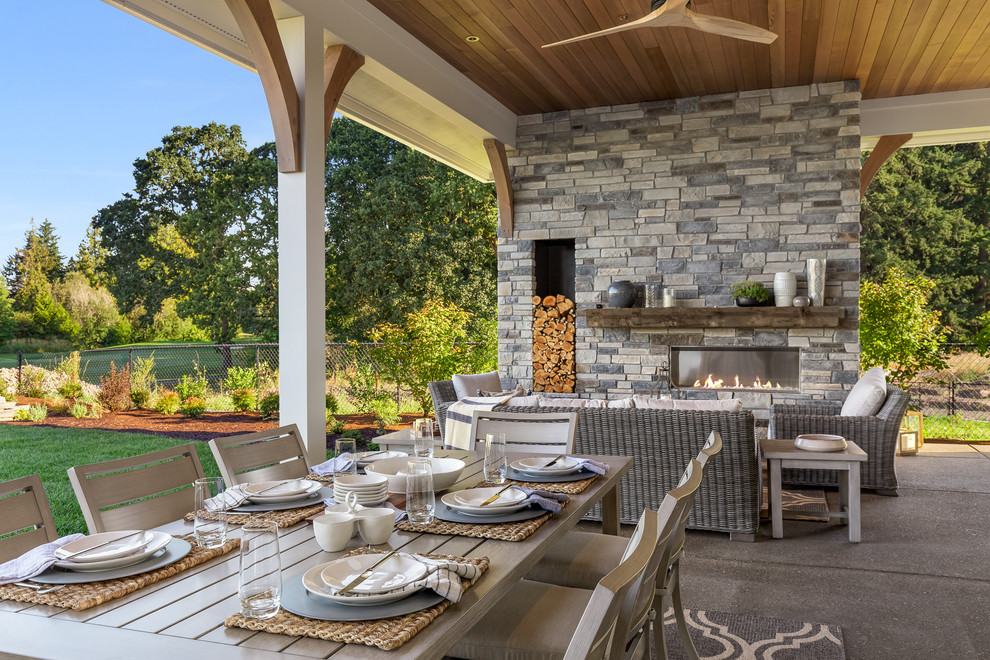 Photo of an expansive country backyard patio in Portland with with fireplace, concrete slab and a roof extension.