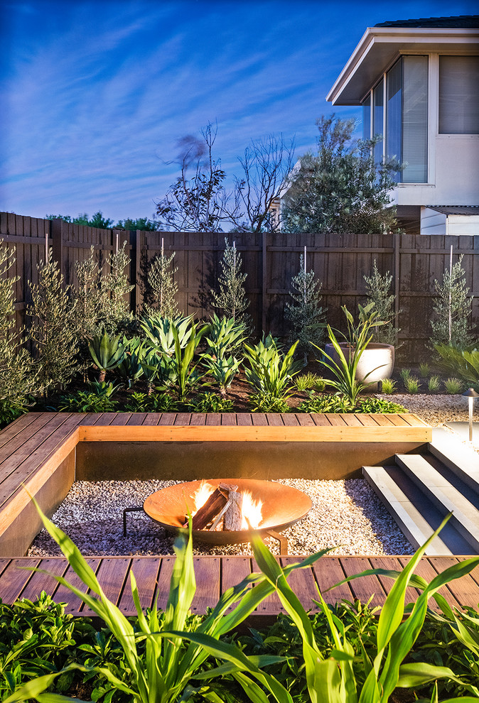 Photo of a mid-sized contemporary backyard full sun garden in Melbourne with a fire feature and gravel.