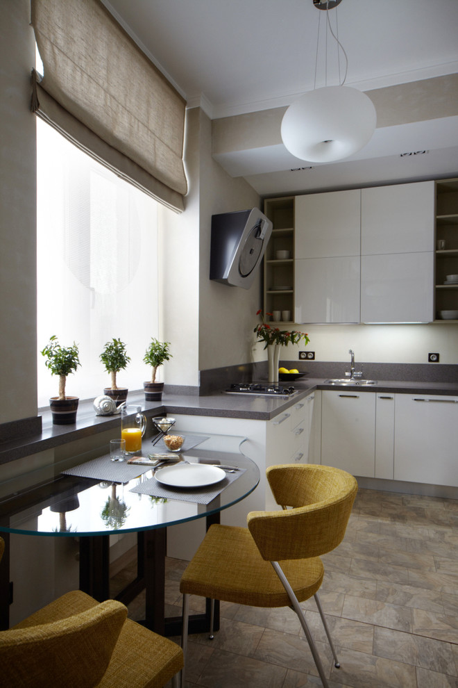 This is an example of a small contemporary l-shaped kitchen in Moscow with a drop-in sink, white cabinets, stainless steel appliances, flat-panel cabinets, white splashback and no island.