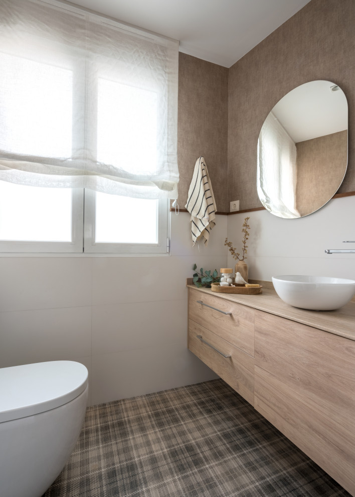 Design ideas for a small transitional powder room in Bilbao with flat-panel cabinets, medium wood cabinets, a one-piece toilet, white tile, ceramic tile, brown walls, ceramic floors, a vessel sink, limestone benchtops, multi-coloured floor, brown benchtops, a built-in vanity and wallpaper.
