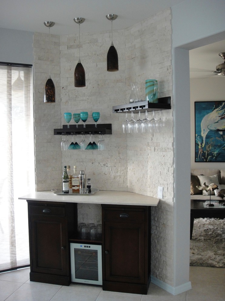 Design ideas for a small beach style single-wall home bar in Miami with no sink, recessed-panel cabinets, black cabinets, limestone benchtops, white splashback, brick splashback and ceramic floors.