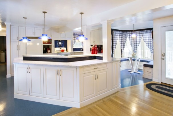 Inspiration for a transitional l-shaped blue floor eat-in kitchen remodel with raised-panel cabinets, white cabinets, blue backsplash, white appliances, an island and white countertops