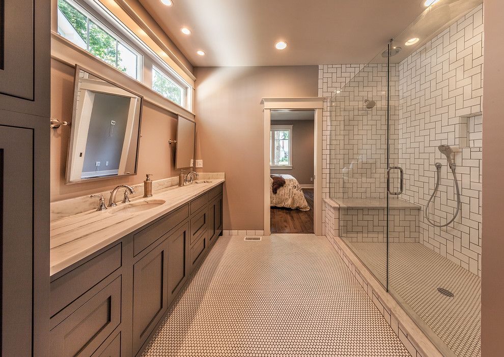This is an example of a large arts and crafts master bathroom in Indianapolis with beaded inset cabinets, dark wood cabinets, an alcove shower, a two-piece toilet, white tile, subway tile, mosaic tile floors, an undermount sink, marble benchtops, white floor and a hinged shower door.
