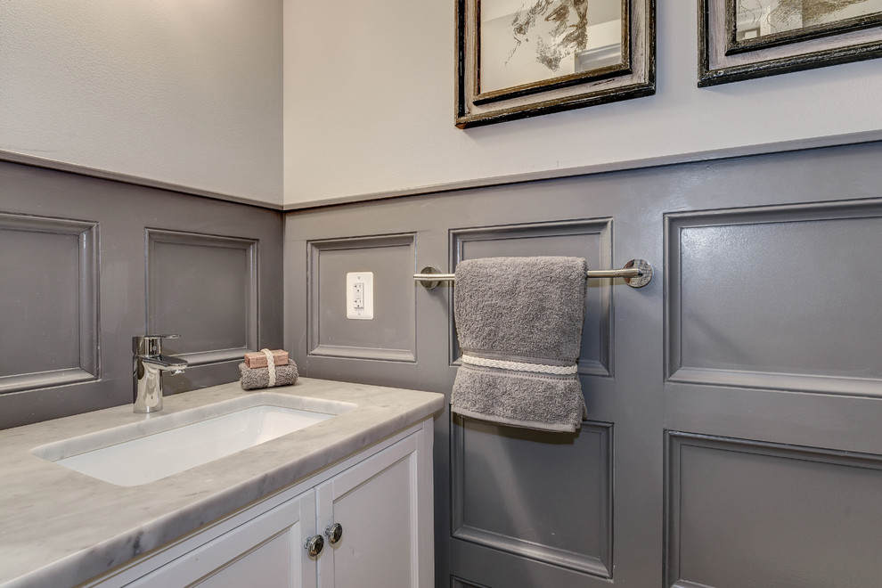 Inspiration for a mid-sized transitional powder room in DC Metro with flat-panel cabinets, white cabinets, a one-piece toilet, grey walls, an undermount sink and marble benchtops.