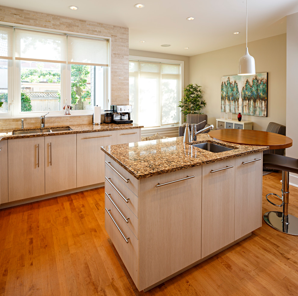Example of a mid-sized transitional l-shaped medium tone wood floor and brown floor eat-in kitchen design in Ottawa with a single-bowl sink, flat-panel cabinets, beige cabinets, granite countertops, beige backsplash, stone tile backsplash, stainless steel appliances and an island