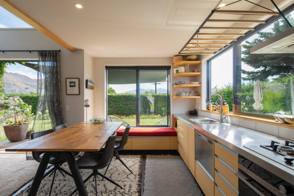 Design ideas for a contemporary single-wall eat-in kitchen in Other with an integrated sink, flat-panel cabinets, medium wood cabinets, stainless steel benchtops, white splashback, black appliances, dark hardwood floors, no island, black floor and grey benchtop.
