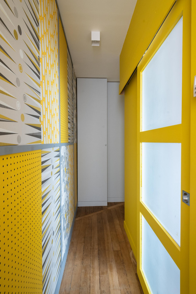 Small eclectic hallway in Paris with yellow walls, light hardwood floors, beige floor and wallpaper.