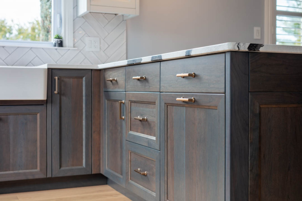 Example of a transitional u-shaped light wood floor open concept kitchen design in Ottawa with a farmhouse sink, recessed-panel cabinets, dark wood cabinets, quartz countertops, white backsplash, porcelain backsplash, paneled appliances, a peninsula and black countertops