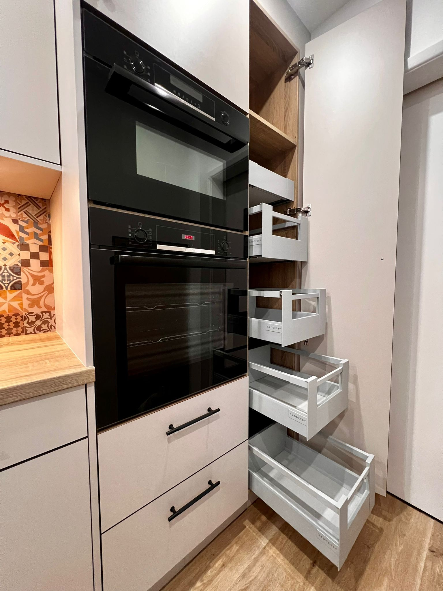 Example of a mid-sized trendy galley vinyl floor and brown floor enclosed kitchen design in Other with flat-panel cabinets, distressed cabinets, laminate countertops, multicolored backsplash, glass sh