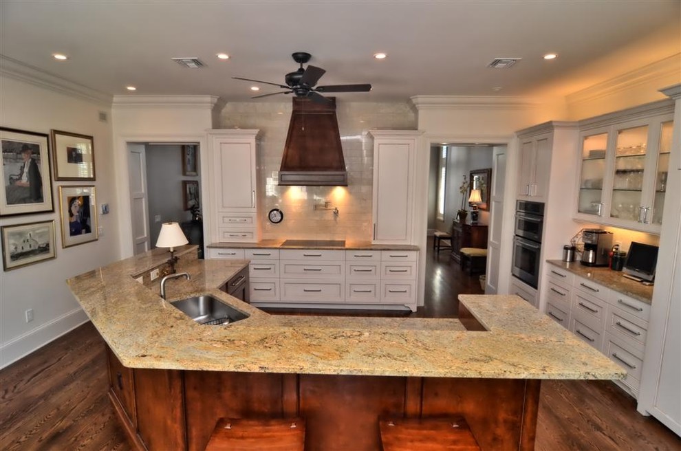 Large traditional l-shaped kitchen in Orlando with a drop-in sink, beaded inset cabinets, white cabinets, granite benchtops, beige splashback, panelled appliances, dark hardwood floors and with island.