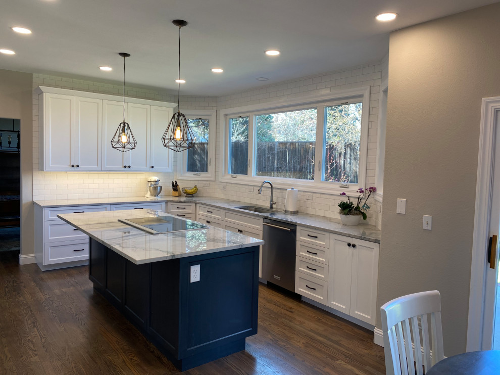 This is an example of a mid-sized transitional u-shaped open plan kitchen in Denver with an undermount sink, shaker cabinets, white cabinets, quartzite benchtops, white splashback, subway tile splashback, stainless steel appliances, medium hardwood floors, with island, brown floor and white benchtop.