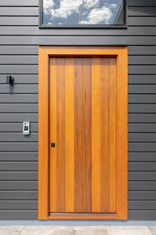 Inspiration for a mid-sized contemporary front door in Brisbane with black walls, ceramic floors, a single front door, a medium wood front door and grey floor.