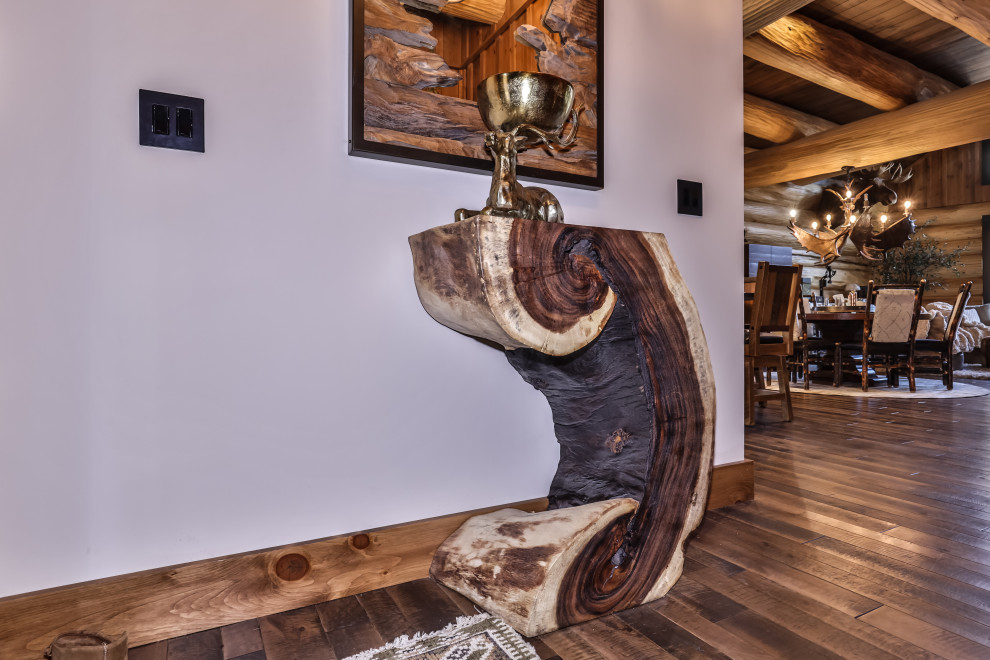 Small mountain style dark wood floor, brown floor and exposed beam entry hall photo with gray walls and a black front door