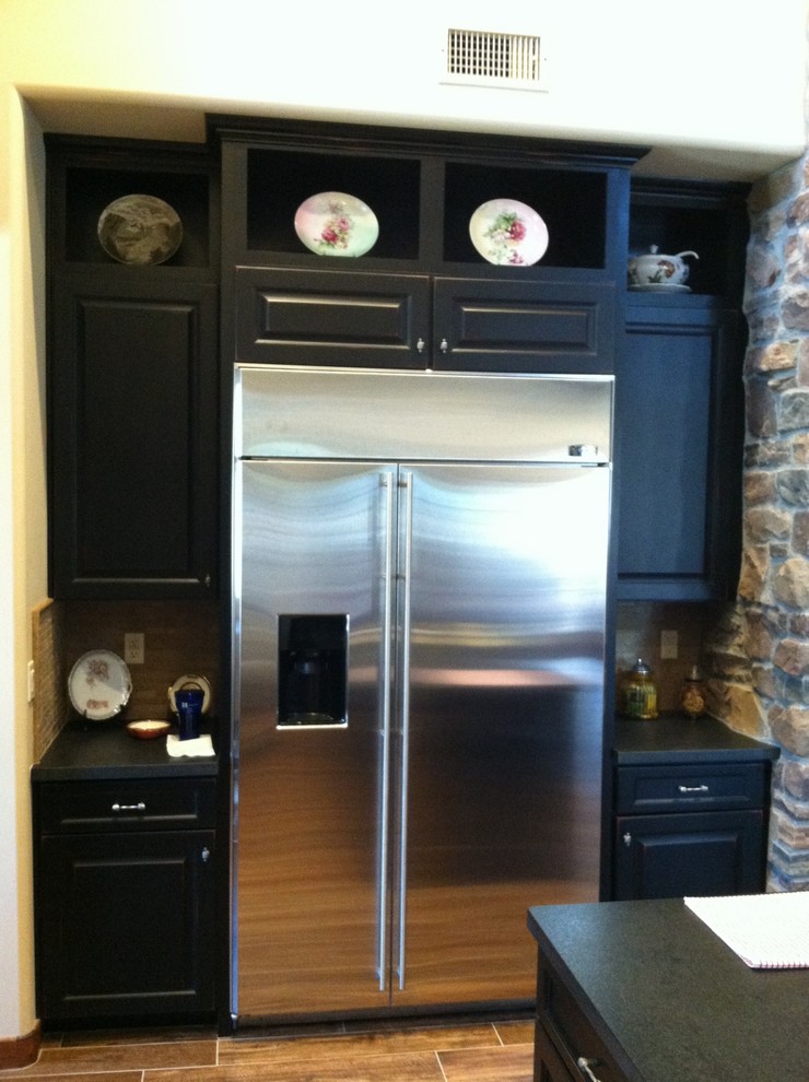 Inspiration for a mid-sized transitional u-shaped medium tone wood floor eat-in kitchen remodel in Phoenix with a double-bowl sink, raised-panel cabinets, black cabinets, granite countertops, white backsplash, subway tile backsplash, stainless steel appliances and no island