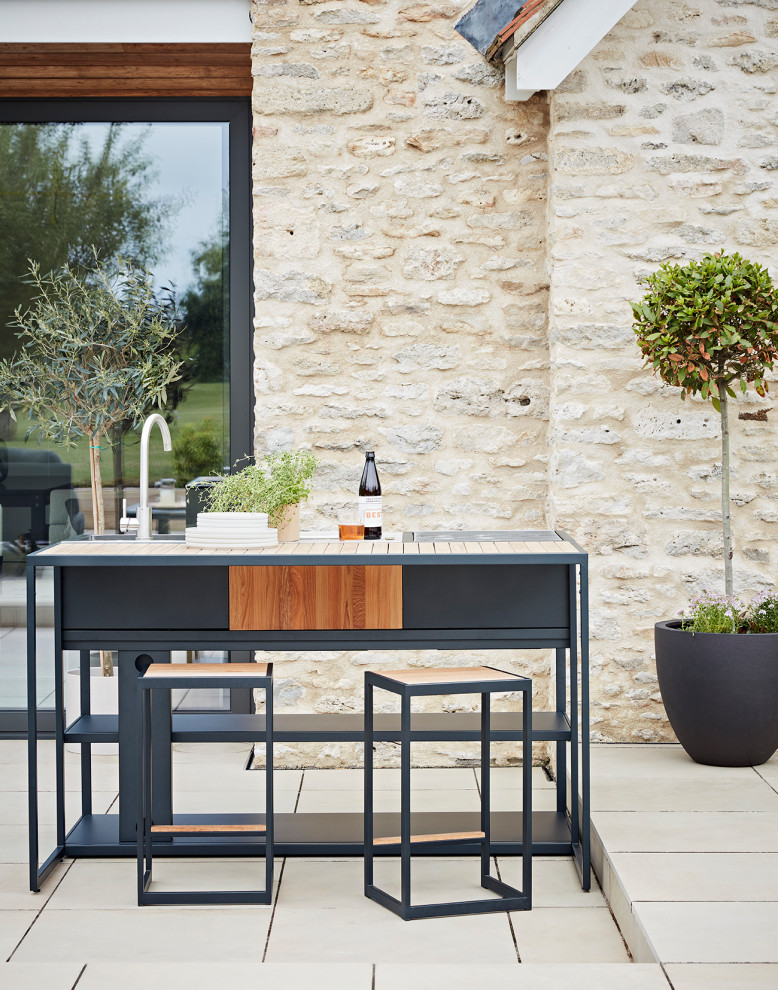 Cette image montre une terrasse design avec une cuisine d'été, des pavés en béton et aucune couverture.