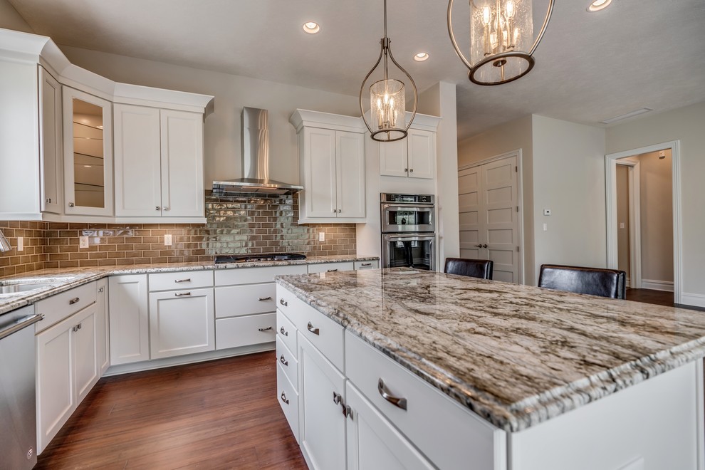 Eat-in kitchen - transitional l-shaped bamboo floor and brown floor eat-in kitchen idea with an undermount sink, flat-panel cabinets, white cabinets, granite countertops, brown backsplash, subway tile backsplash, stainless steel appliances, an island and brown countertops