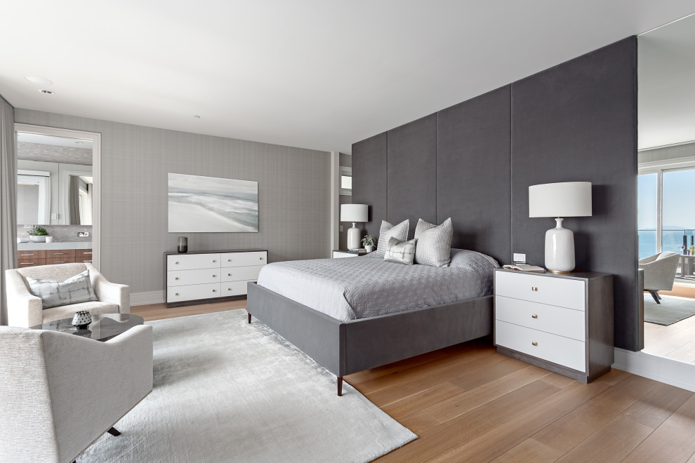 Photo of a large beach style master bedroom in Vancouver with grey walls, medium hardwood floors and brown floor.