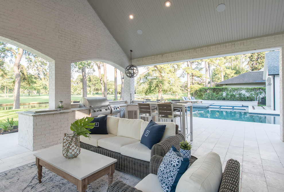 This is an example of a large beach style backyard patio in Houston with an outdoor kitchen, tile and a roof extension.