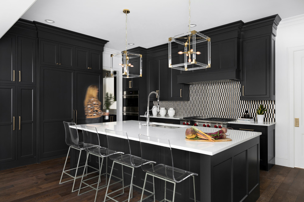 This is an example of a large eclectic galley open plan kitchen in Minneapolis with a farmhouse sink, recessed-panel cabinets, black cabinets, granite benchtops, multi-coloured splashback, ceramic splashback, stainless steel appliances, dark hardwood floors, with island, brown floor and white benchtop.