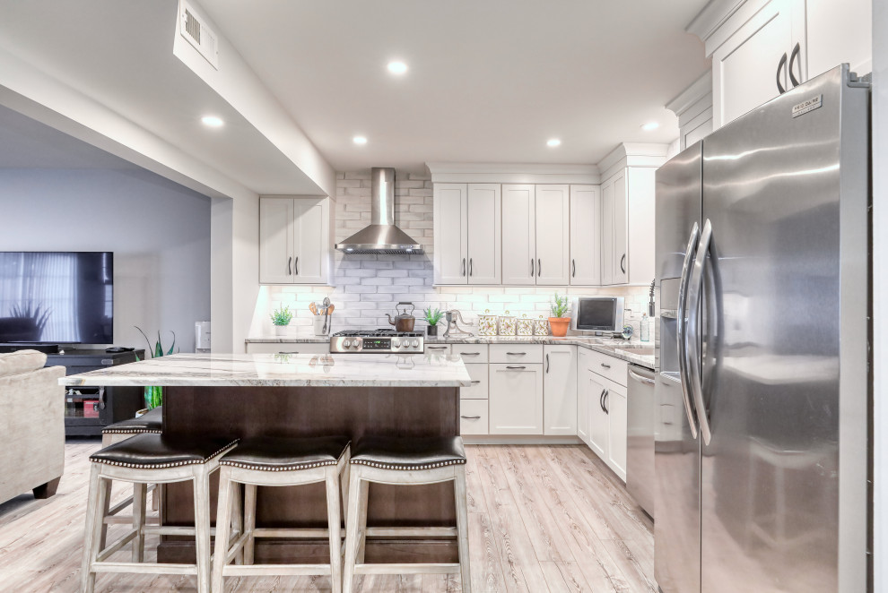 Bild på ett mellanstort funkis flerfärgad flerfärgat kök, med en undermonterad diskho, skåp i shakerstil, vita skåp, bänkskiva i kvartsit, grått stänkskydd, stänkskydd i tunnelbanekakel, rostfria vitvaror, ljust trägolv, en köksö och brunt golv