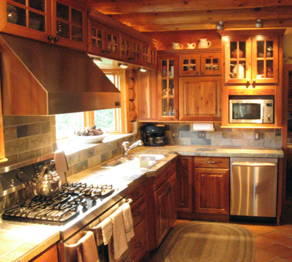 Photo of a mid-sized country l-shaped separate kitchen in Austin with a double-bowl sink, raised-panel cabinets, dark wood cabinets, tile benchtops, multi-coloured splashback, slate splashback, stainless steel appliances, terra-cotta floors, no island, orange floor and multi-coloured benchtop.