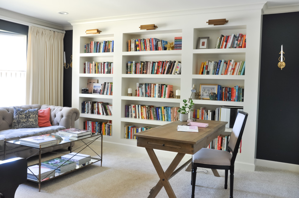 Photo of a large transitional home office with a library, blue walls, carpet and a freestanding desk.