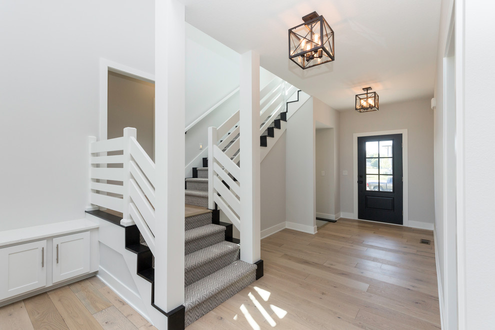 Country entryway in Other with grey walls, light hardwood floors and a black front door.
