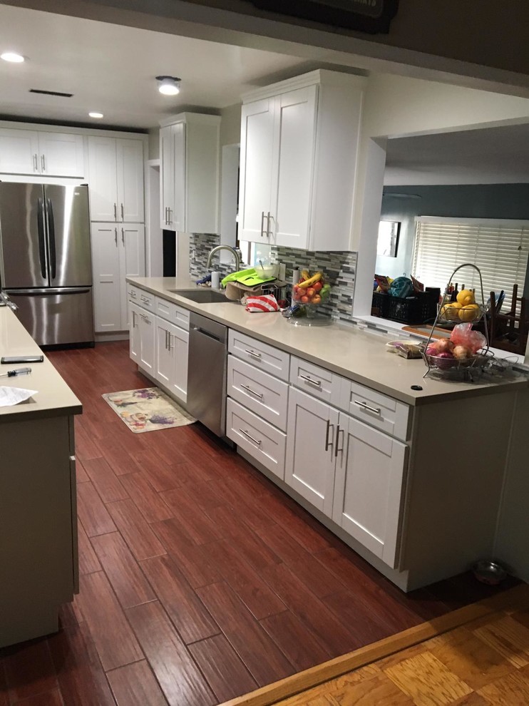 Inspiration for a small transitional kitchen in Los Angeles with an undermount sink, shaker cabinets, white cabinets, solid surface benchtops, grey splashback, matchstick tile splashback, stainless steel appliances, medium hardwood floors, no island, blue floor and grey benchtop.