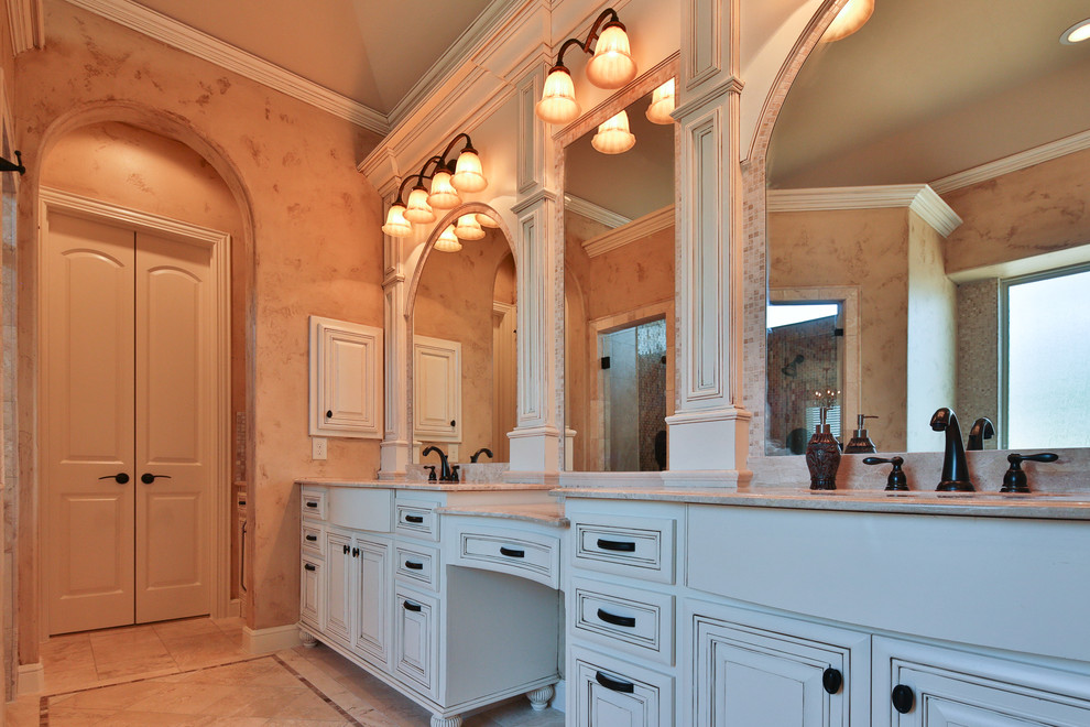 Photo of a large traditional master bathroom in Dallas with raised-panel cabinets, white cabinets, a drop-in tub, beige tile, mosaic tile, beige walls, travertine floors, an undermount sink, granite benchtops, an alcove shower and beige floor.