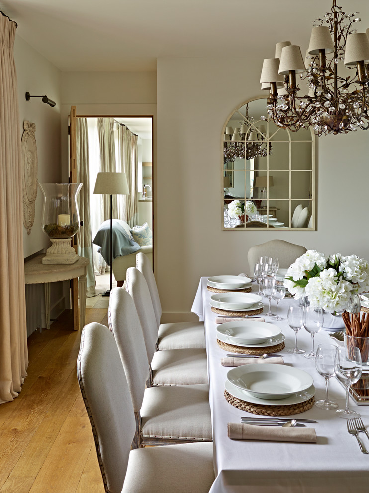 This is an example of a separate dining room in London with beige walls and light hardwood floors.