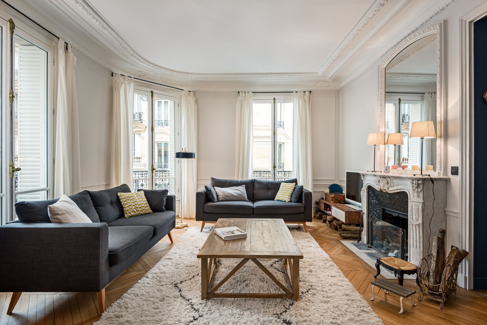 Inspiration for a mid-sized transitional living room in Paris with white walls, a standard fireplace, a freestanding tv, medium hardwood floors and brown floor.