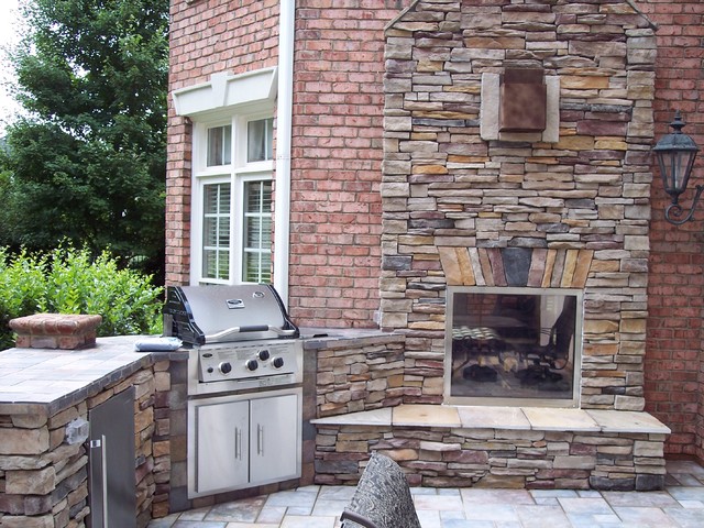 Beautiful exterior photo of a double sided exterior/interior gas fireplace with stone veneer and slate hearth.