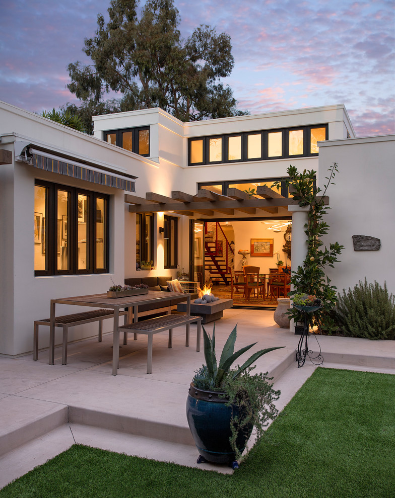 This is an example of a mid-sized mediterranean backyard patio in Santa Barbara with a fire feature, concrete slab and a pergola.