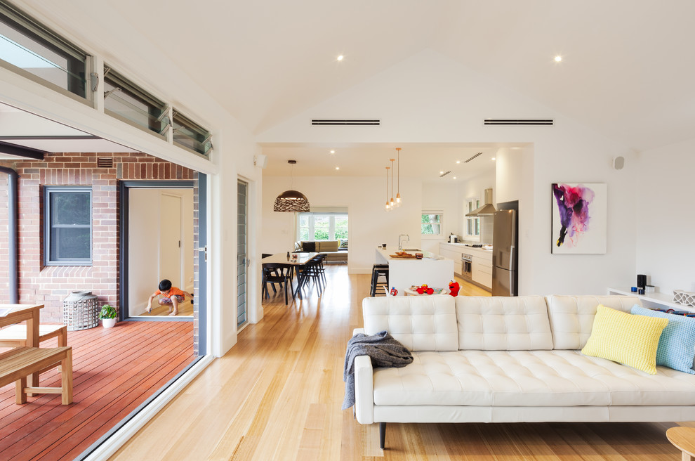 This is an example of a mid-sized contemporary open concept living room in Sydney with white walls, light hardwood floors, no fireplace and no tv.