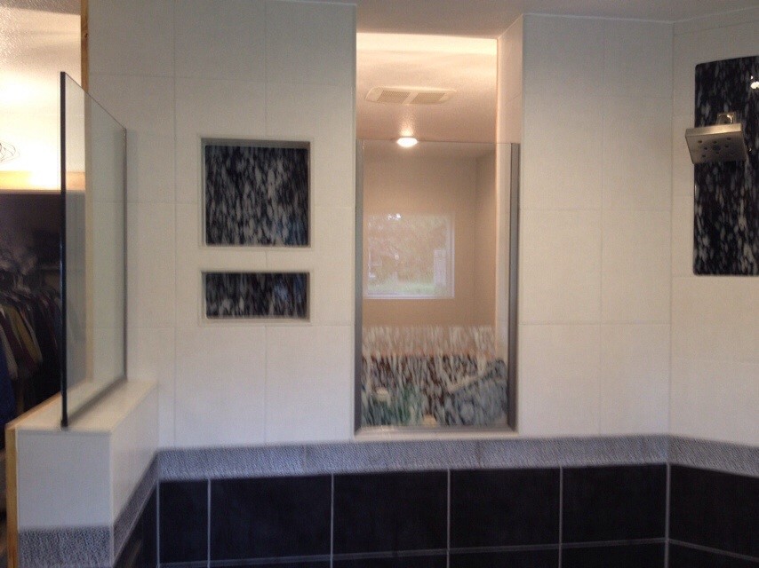 Example of a mountain style master black tile and glass tile porcelain tile walk-in shower design in Denver with an integrated sink, furniture-like cabinets, medium tone wood cabinets, concrete countertops, a one-piece toilet and brown walls