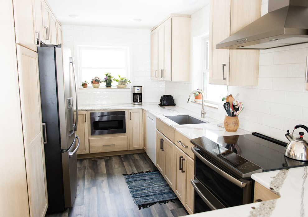 Inspiration for a mid-sized transitional u-shaped vinyl floor and brown floor enclosed kitchen remodel with an undermount sink, flat-panel cabinets, beige cabinets, quartz countertops, white backsplash, subway tile backsplash, black appliances, a peninsula and white countertops