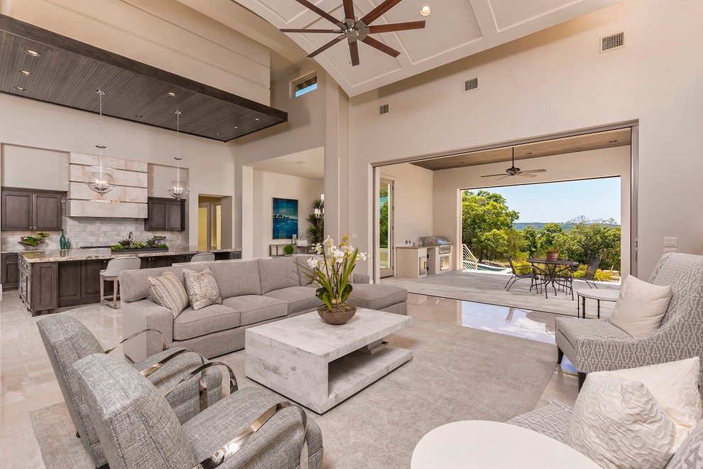 This is an example of a mid-sized mediterranean open concept family room in Austin with beige walls, marble floors, no fireplace, no tv and beige floor.