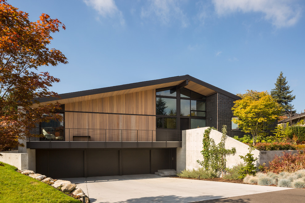 This is an example of a large midcentury two-storey brick black exterior in Seattle with a gable roof.